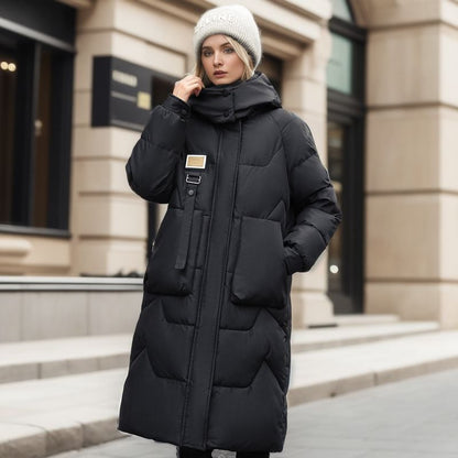 Donna con cappotto lungo nero invernale, cappello di lana grigio, cammina in città. Moda invernale, abbigliamento caldo, stile urbano elegante.