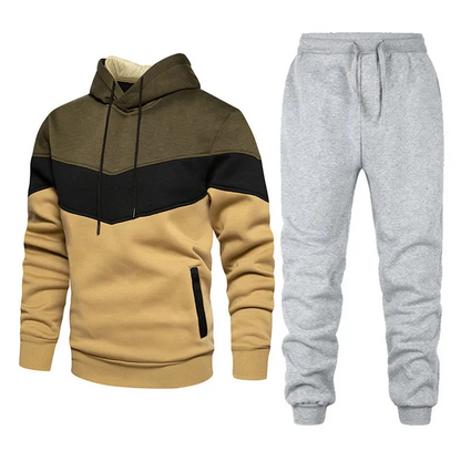 Tuta sportiva uomo: felpa con cappuccio a blocchi di colore marrone, nero e beige, pantaloni grigi. Abbigliamento casual e comodo.