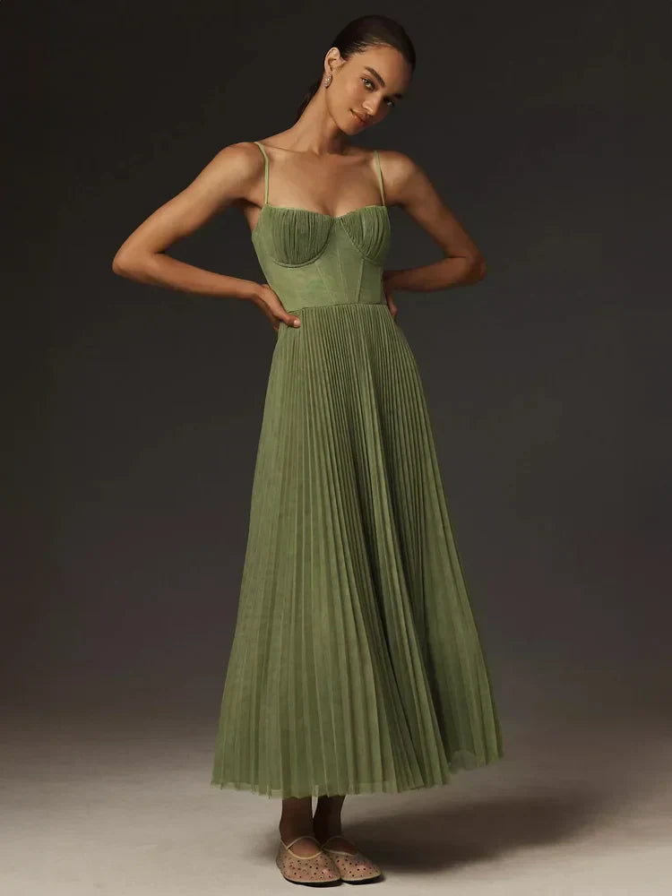 Donna in abito lungo verde plissettato, spalline sottili, posa elegante. Moda femminile, abbigliamento elegante, tendenze abiti da sera.