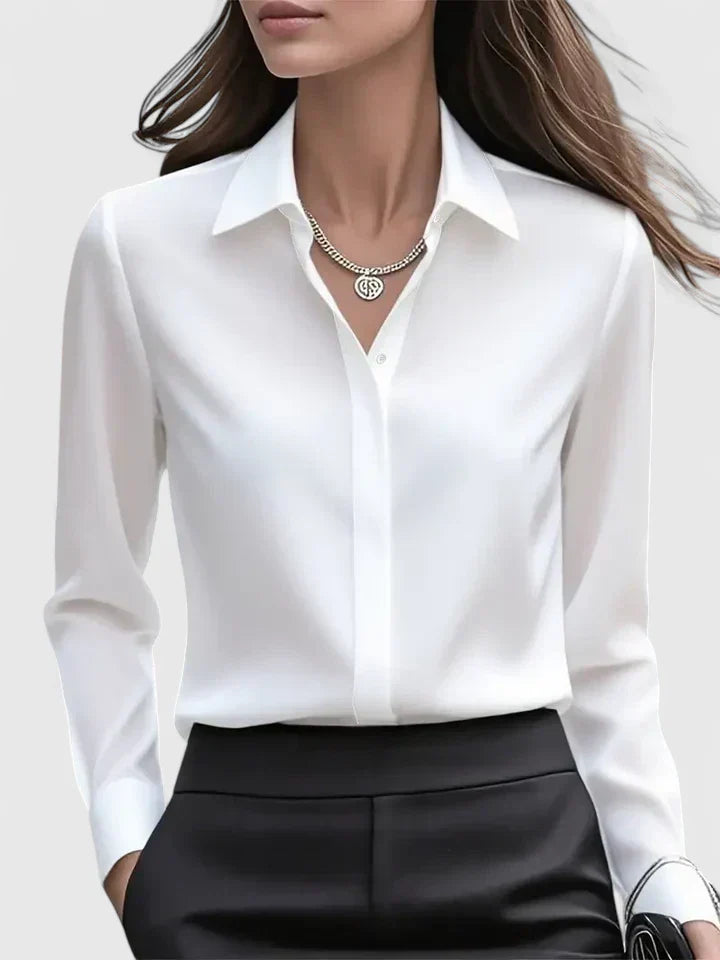 Donna in camicia bianca elegante e pantaloni neri, collana d'argento. Moda business casual, abbigliamento da ufficio, stile professionale.
