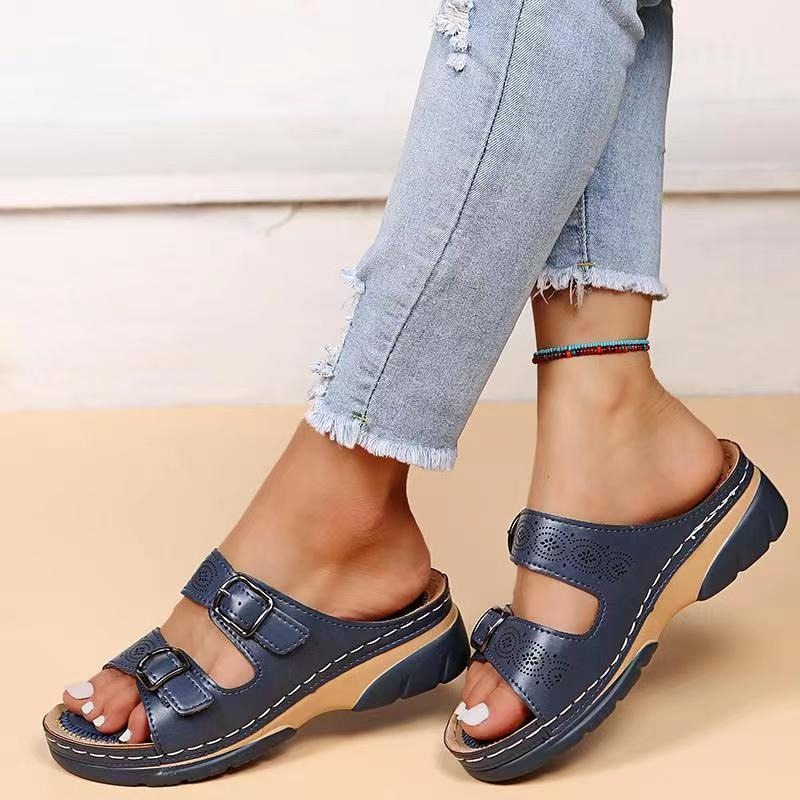 Jeans strappati e sandali blu con fibbie su piedi femminili, cavigliera colorata. Scarpe estive comode, moda casual donna.