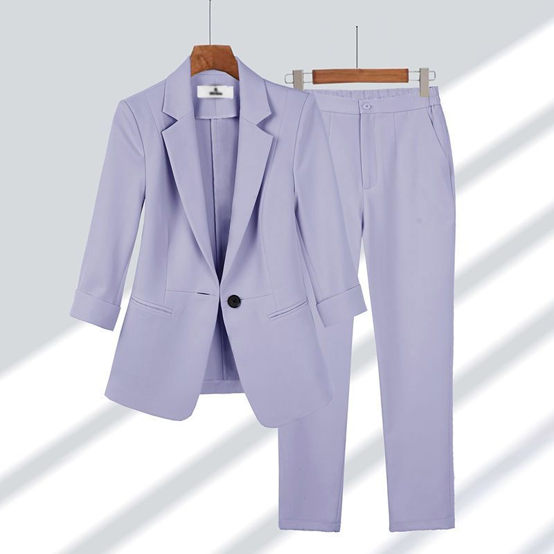 Completo donna elegante color lavanda, giacca e pantaloni abbinati, appesi su grucce. Moda femminile, abbigliamento formale, tendenza 2023.