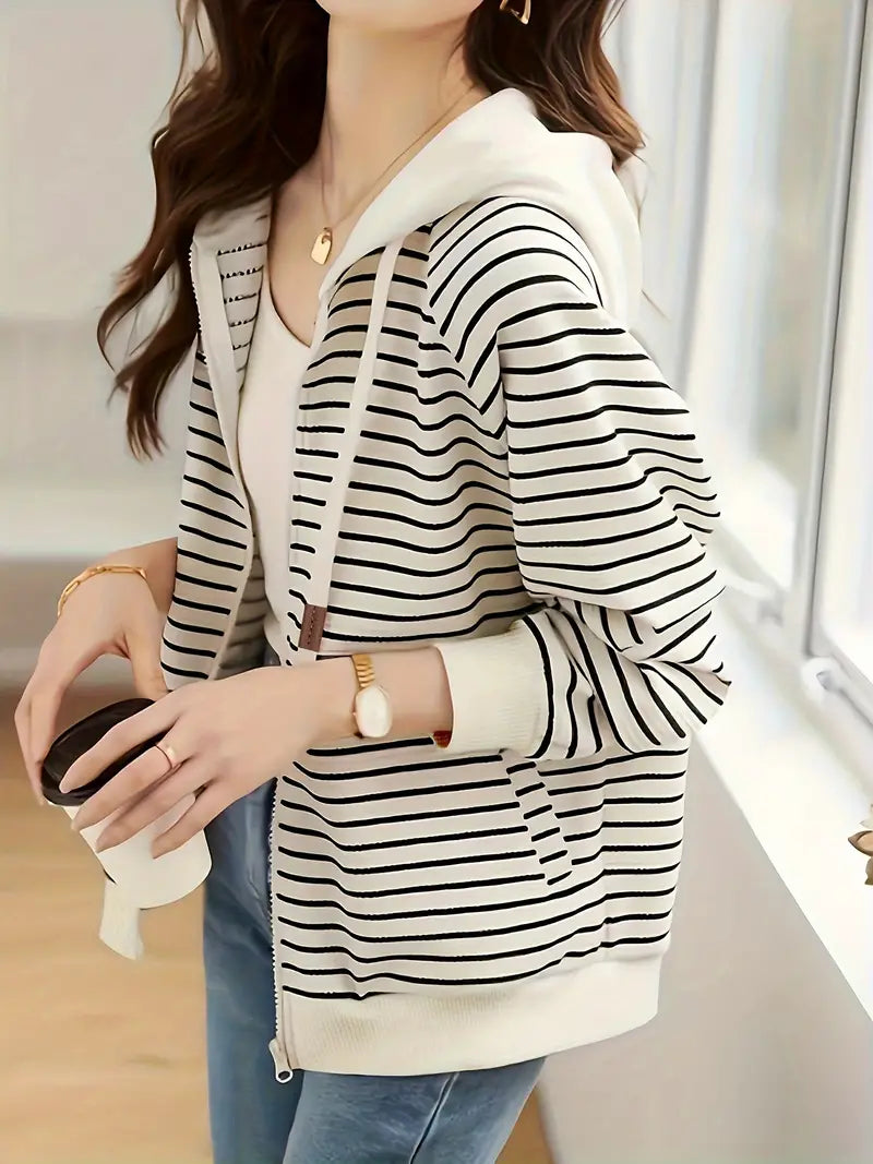 Donna con felpa a righe bianche e nere, cappuccio, e cerniera, tiene una tazza di caffè. Look casual, moda autunnale, abbigliamento femminile trendy.