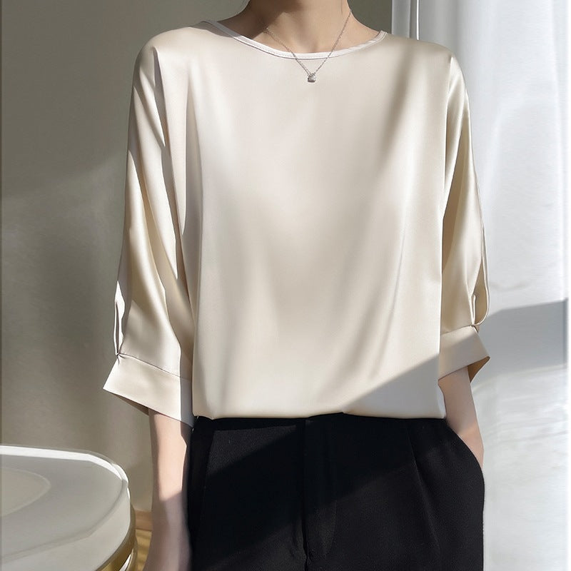 Camicia di seta bianca elegante, maniche a tre quarti, indossata con pantaloni neri. Moda minimalista, abbigliamento femminile chic.