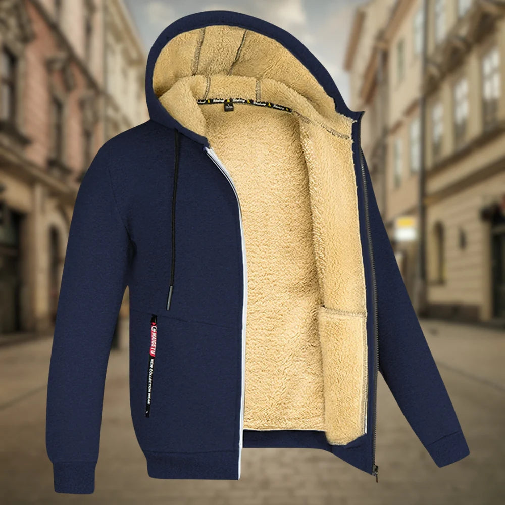 Giacca invernale con cappuccio blu scuro, interno in pelliccia sintetica beige, zip frontale, su sfondo urbano sfocato. Moda uomo, abbigliamento caldo.