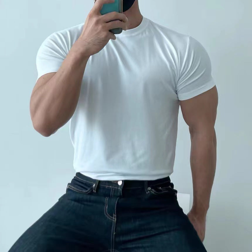 Uomo muscoloso in t-shirt bianca e jeans scuri, scatta un selfie con smartphone. Moda casual maschile, abbigliamento estivo, fitness.