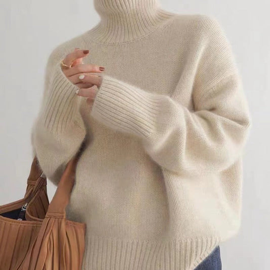 Maglione a collo alto beige in lana, indossato da una persona che tiene una borsa marrone. Stile casual, moda autunnale, abbigliamento caldo.