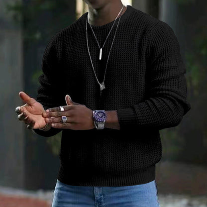 Uomo con maglione nero a maglia, orologio elegante e collane, sfondo urbano sfocato. Moda maschile, accessori di tendenza.