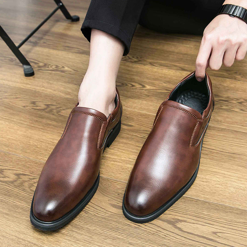 Scarpe eleganti in pelle marrone per uomo su pavimento in legno, design slip-on, ideali per abbigliamento formale e business casual.