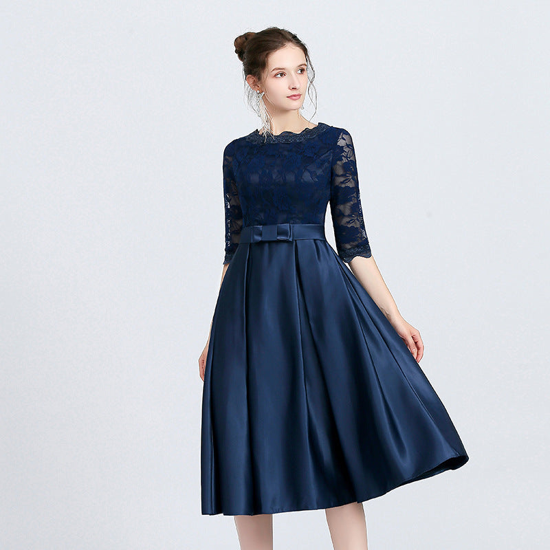 Donna in abito da sera blu scuro in pizzo e raso, maniche a tre quarti, lunghezza al ginocchio, elegante e sofisticato. Moda femminile elegante.