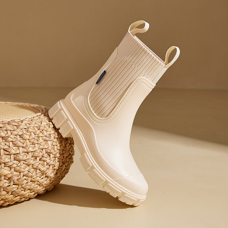 Stivale da pioggia beige su sfondo neutro, design moderno con suola robusta e dettagli a coste. Calzature impermeabili eleganti per donna.