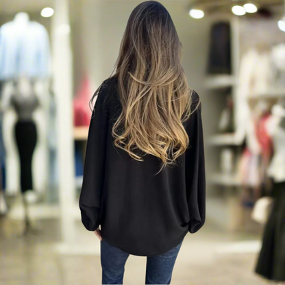 Donna di spalle con capelli lunghi e ondulati in negozio di abbigliamento, indossa camicia nera e jeans. Moda femminile, shopping, stile casual.