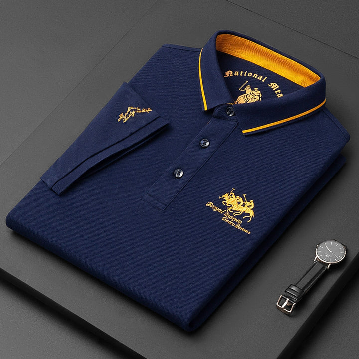 Camicia polo blu scuro piegata con colletto giallo, logo ricamato, orologio nero accanto. Moda uomo elegante, abbigliamento casual di lusso.