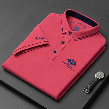 Polo rossa piegata con logo ricamato, colletto a contrasto e orologio nero accanto. Moda uomo elegante, abbigliamento casual di qualità.