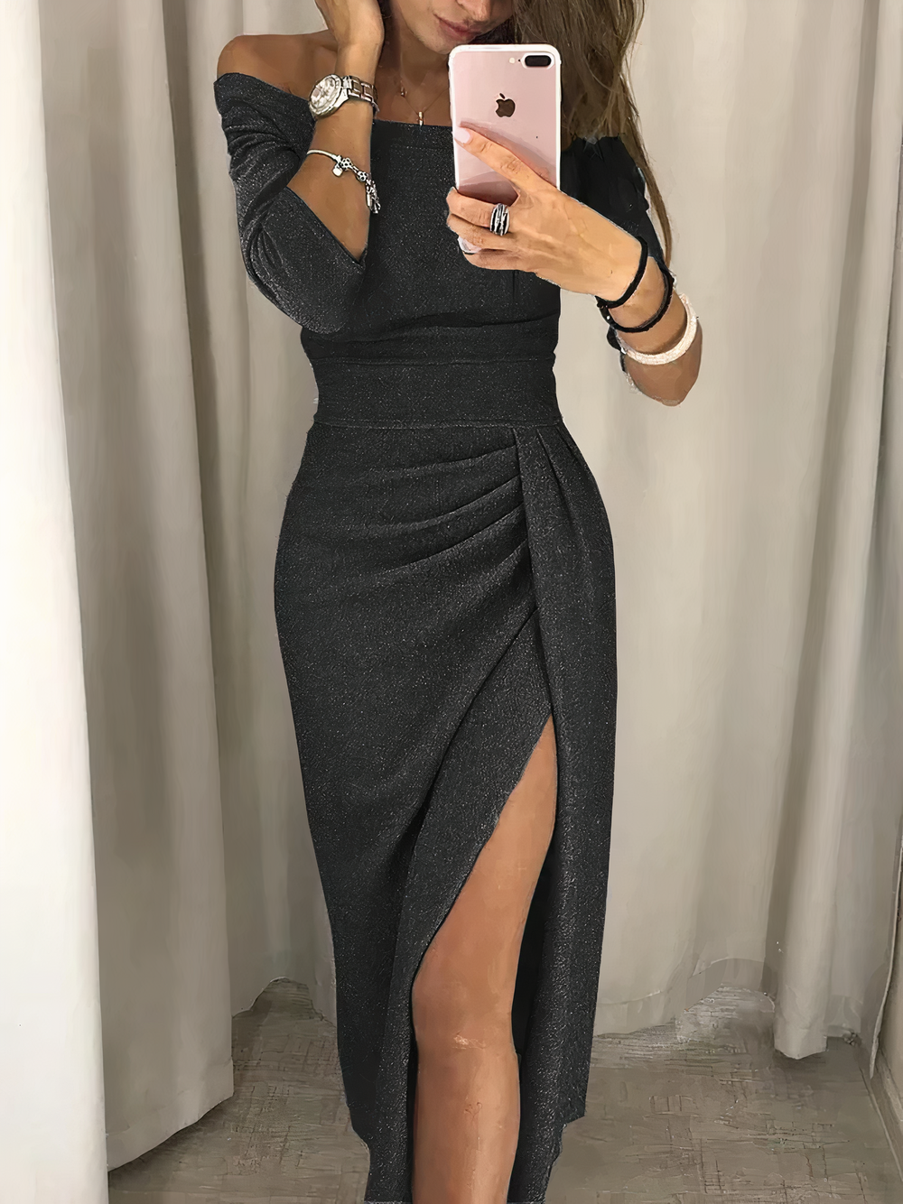 Abito lungo nero elegante con spacco alto, indossato da donna che tiene uno smartphone rosa. Moda femminile, abbigliamento da sera chic.