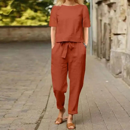 Donna con completo estivo arancione, pantaloni e maglietta, cammina su strada lastricata. Moda casual, abbigliamento estivo, stile urbano.
