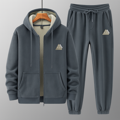 Tuta sportiva grigia in pile con cappuccio e pantaloni, design moderno, tasche frontali, ideale per abbigliamento casual e attività all'aperto.