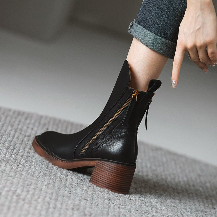 Stivaletto nero in pelle con tacco largo e cerniera dorata, indossato con jeans. Scarpe moda autunno inverno, stile casual chic.