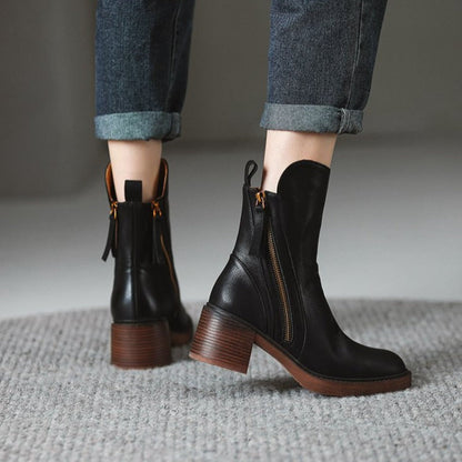 Stivaletti neri in pelle con tacco largo, zip laterale dorata, indossati con jeans risvoltati. Scarpe moda autunno inverno donna.