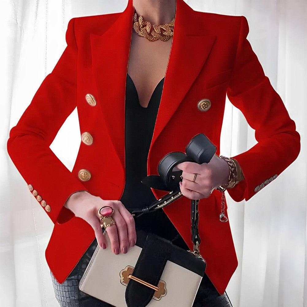 Donna in giacca rossa elegante con bottoni dorati, indossa gioielli e tiene una borsa bianca e nera. Stile moda femminile, abbigliamento chic.