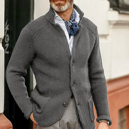 Uomo con cardigan grigio a maglia grossa, camicia bianca e foulard blu. Moda maschile elegante, abbigliamento autunnale casual chic.