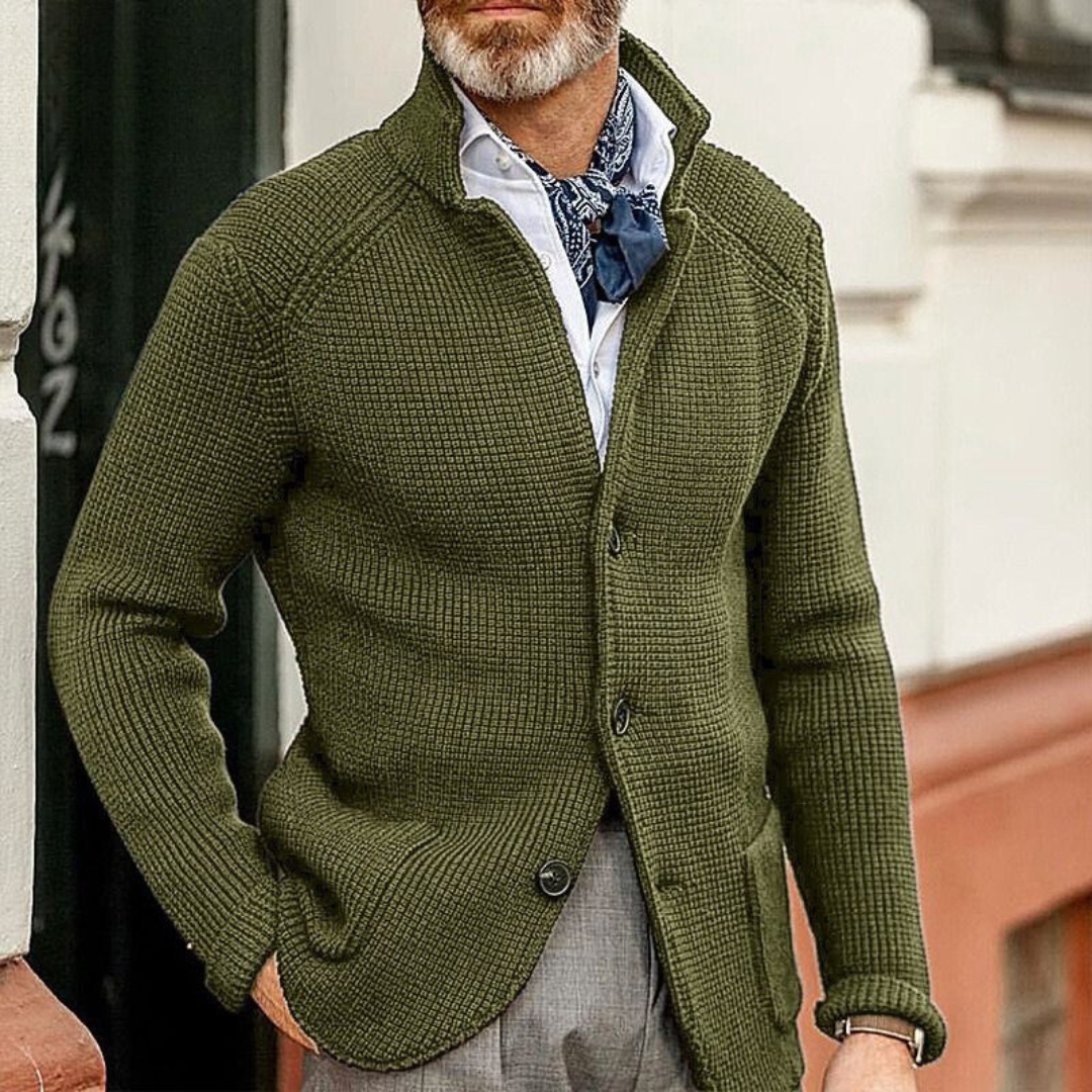 Uomo con cardigan verde oliva a maglia grossa, camicia bianca e foulard blu, moda autunnale elegante, stile casual chic maschile.