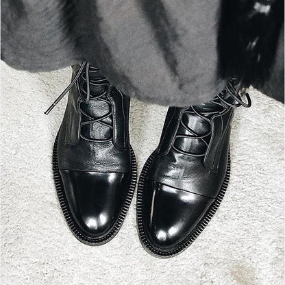 Women's mid-calf lace-up boots with a flat sole and British-inspired design.