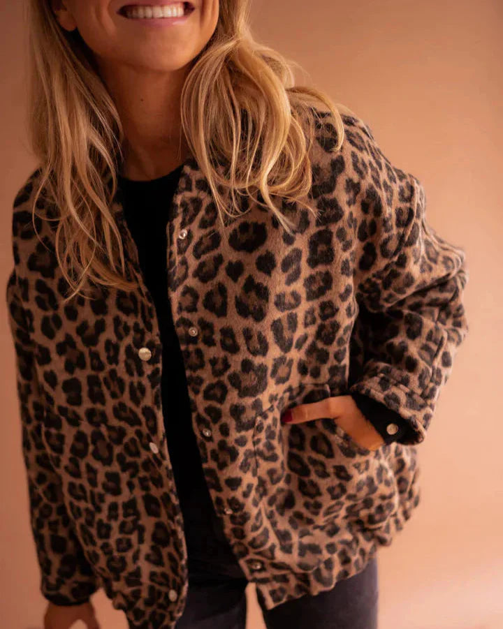 Donna con giacca leopardata, sfondo beige. Moda autunno, stile casual chic, tendenze abbigliamento femminile. Look elegante e moderno.