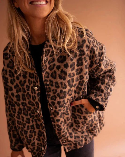 Donna con giacca leopardata, sfondo beige. Moda autunno, stile casual chic, tendenze abbigliamento femminile. Look elegante e moderno.