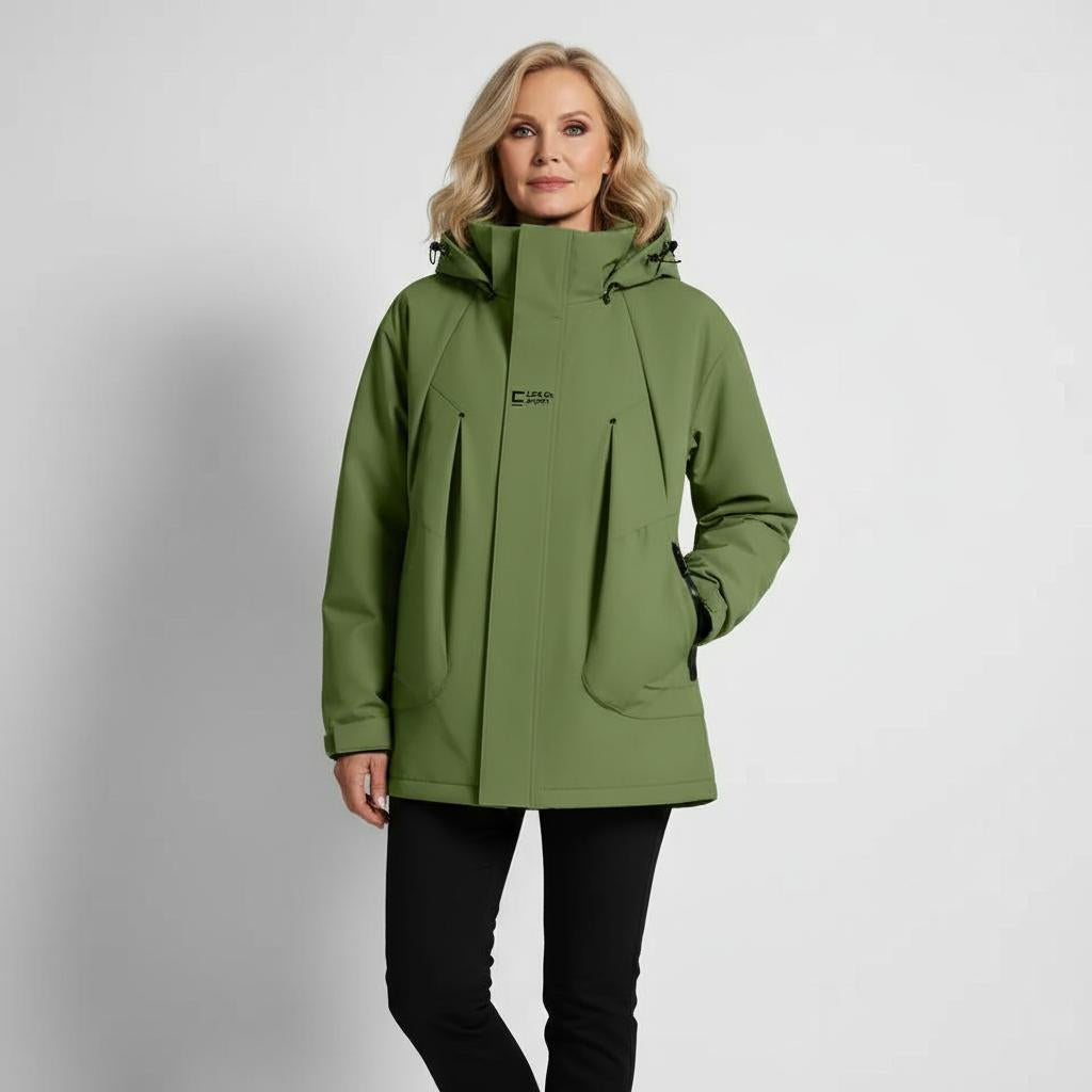 Donna in giacca verde impermeabile con cappuccio, design moderno, ideale per escursioni e attività outdoor. Abbigliamento tecnico, moda autunno-inverno.