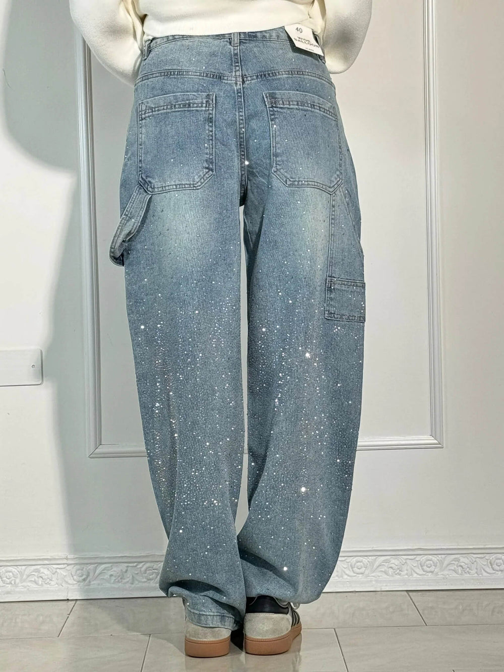 Jeans larghi da donna con tasche posteriori e laterali, effetto glitter, indossati da una persona di spalle. Moda casual, tendenza denim.