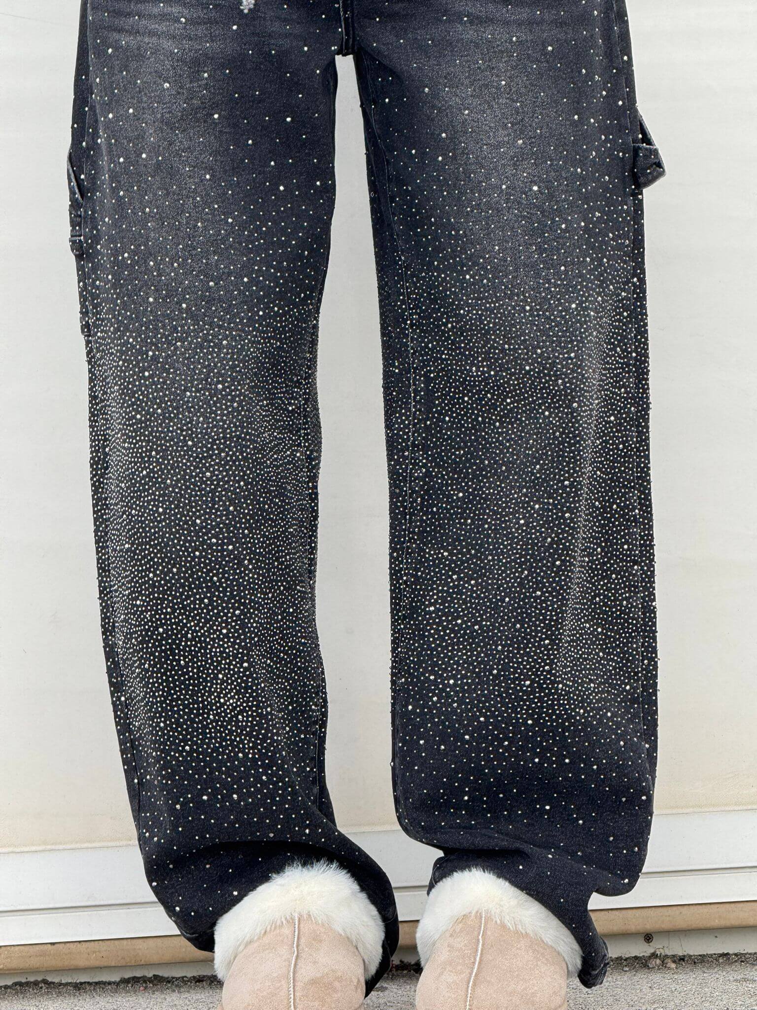 Jeans neri con strass scintillanti, abbinati a stivali beige con pelliccia. Moda invernale, abbigliamento casual elegante.