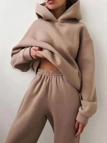 Donna in tuta beige, felpa con cappuccio e pantaloni larghi. Moda casual, abbigliamento comodo, stile autunnale.