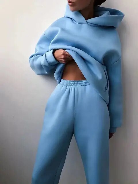 Donna in tuta sportiva azzurra, felpa con cappuccio e pantaloni comodi. Moda casual, abbigliamento sportivo, stile rilassato.