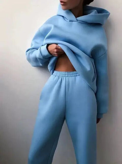 Donna in tuta sportiva azzurra, felpa con cappuccio e pantaloni comodi. Moda casual, abbigliamento sportivo, stile rilassato.