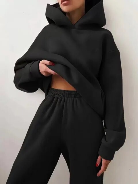 Donna con felpa nera oversize e pantaloni coordinati, moda casual, abbigliamento comodo, stile streetwear, tendenza autunno inverno.
