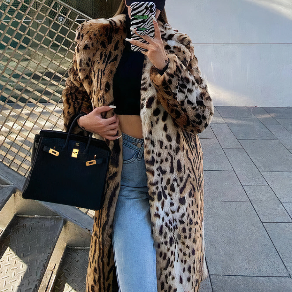 Donna con cappotto leopardato, jeans a vita alta, borsa nera di lusso, posa su scala urbana. Moda autunnale, stile elegante, tendenze 2023.