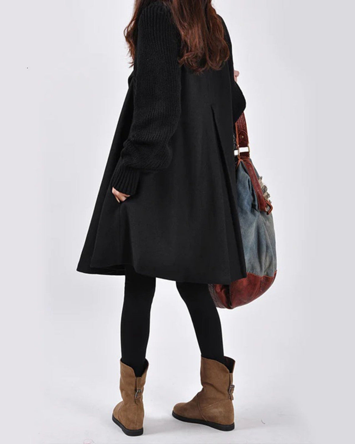 Donna di spalle con cappotto nero, leggings e stivali marroni, borsa a tracolla in tessuto. Moda autunnale, abbigliamento casual elegante.