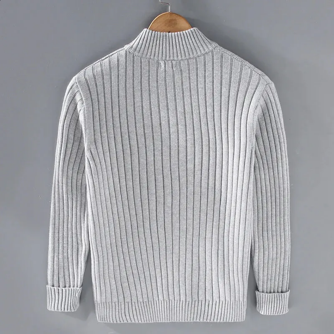 Maglione grigio a coste, maniche lunghe, appeso su gruccia di legno. Design elegante e moderno, ideale per moda autunnale e invernale.