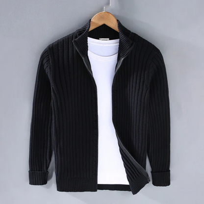 Cardigan nero a coste con zip, appeso su gruccia, sopra maglietta bianca. Moda uomo, abbigliamento casual, stile autunnale.