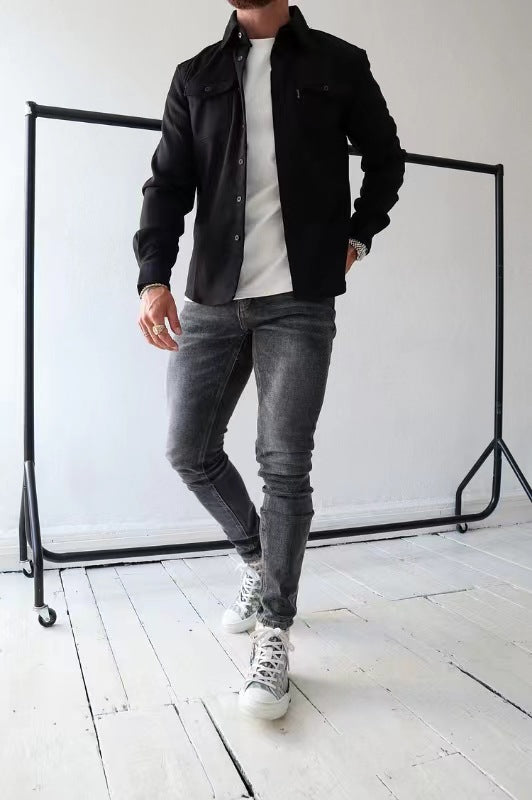 Uomo in jeans grigi e giacca nera su sfondo bianco, posa casual. Moda maschile, abbigliamento moderno, stile urbano.