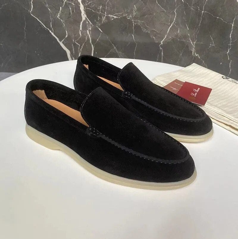 Scarpe mocassini uomo in pelle scamosciata nera su tavolo bianco, sfondo marmo grigio. Eleganti, suola chiara, moda maschile, calzature di lusso.