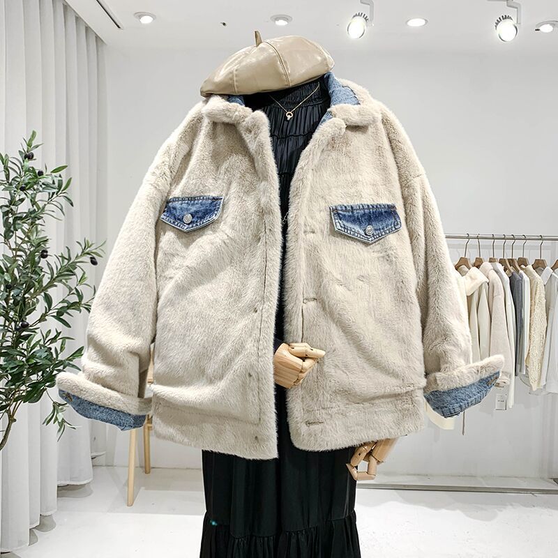 Giacca in pelliccia sintetica beige con dettagli in denim, esposta su manichino in negozio di moda. Elegante e calda, perfetta per l'inverno.