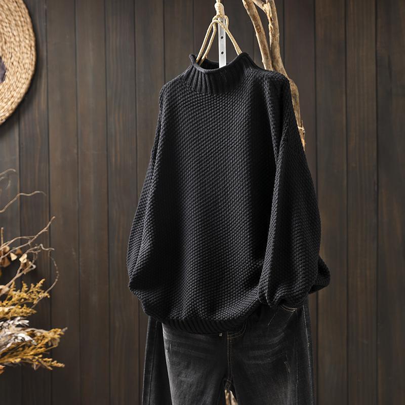 Maglione nero a collo alto in maglia spessa, appeso su sfondo di legno scuro, moda autunno inverno, abbigliamento casual elegante.