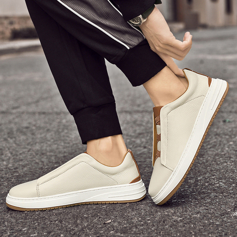 Scarpe da ginnastica bianche da uomo, design slip-on, suola in gomma, indossate su strada asfaltata. Moda casual, comfort, stile urbano.