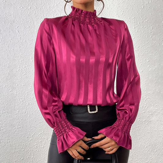 Camicia elegante in raso rosa con colletto alto e maniche a sbuffo, abbinata a pantaloni in pelle nera. Moda femminile, stile sofisticato.