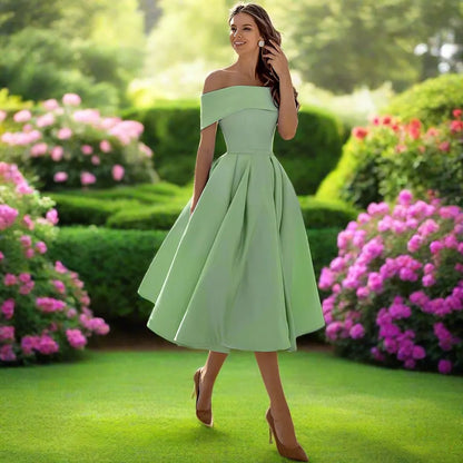Donna in abito verde elegante in giardino fiorito, circondata da cespugli di ortensie rosa. Moda estiva, stile sofisticato, natura rigogliosa.