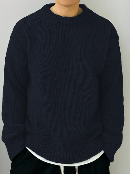 Maglione blu scuro in maglia pesante, indossato da una persona, con collo rotondo e maniche lunghe. Stile casual, moda autunno-inverno.