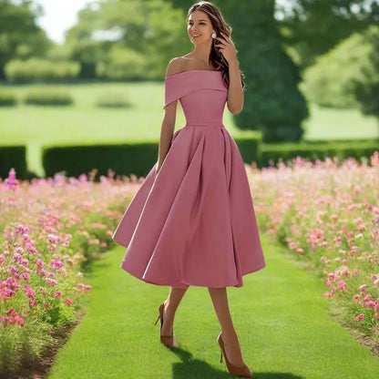 Donna in abito rosa elegante in un giardino fiorito, cammina su un sentiero verde. Moda femminile, abbigliamento estivo, stile sofisticato.