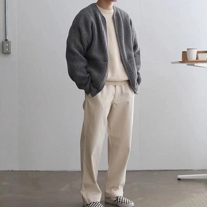 Uomo in abbigliamento casual: cardigan grigio, maglia beige, pantaloni chiari, scarpe a scacchi. Moda autunnale minimalista, stile urbano.
